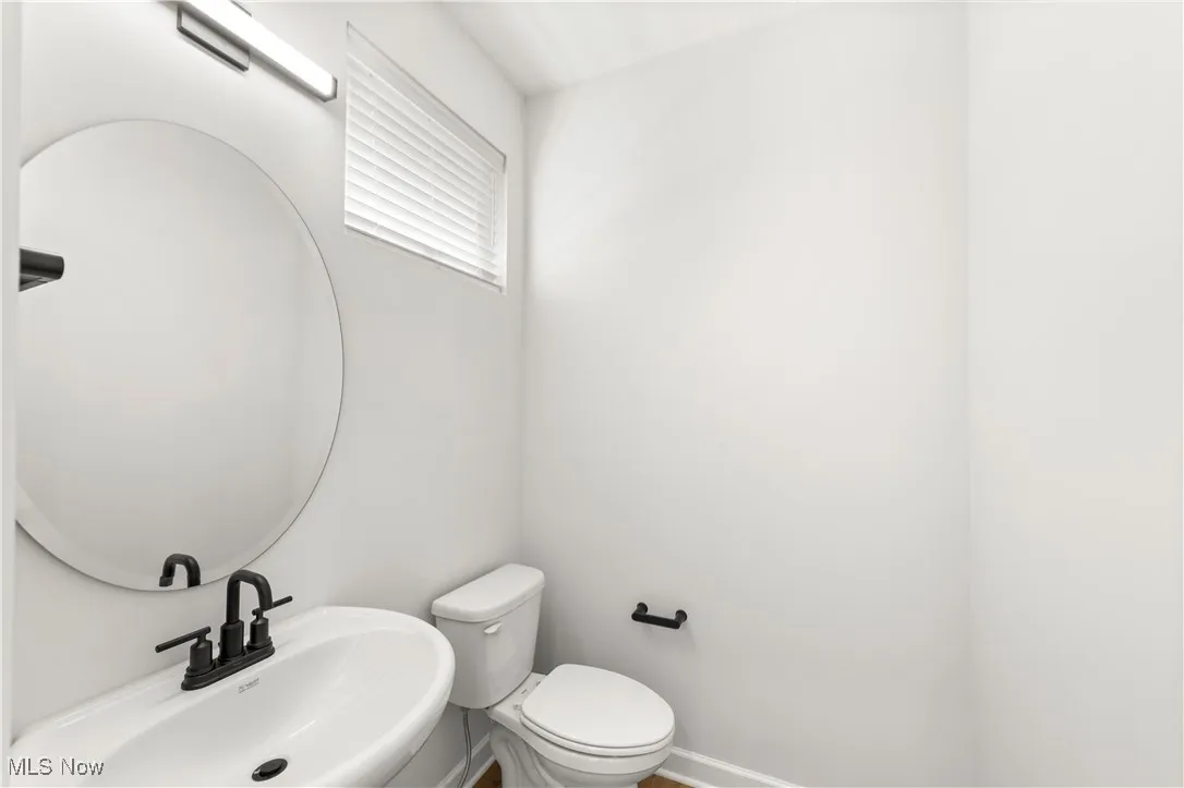 Half bath with a sink, toilet, and baseboards