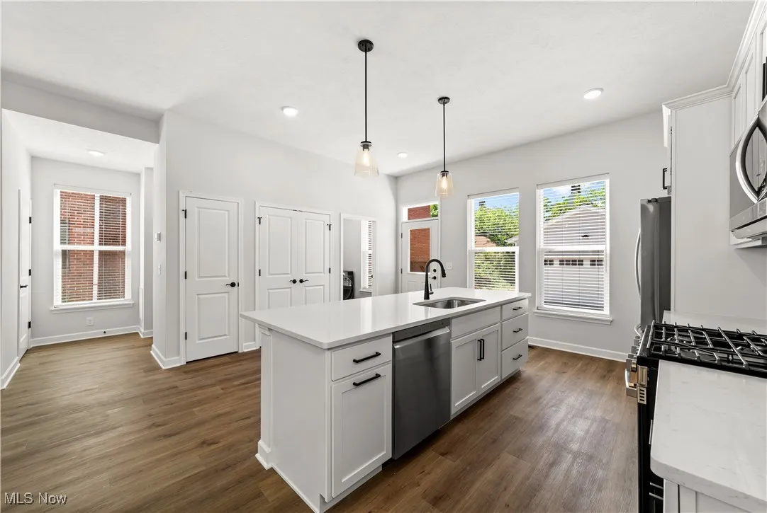 Kitchen featuring stainless steel appliances, a sink, an island with sink, dark wood finished floors, and recessed lighting