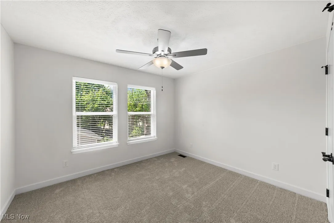 Empty room featuring baseboards, light colored carpet, and ceiling fan