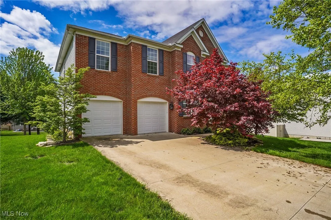 View of front of house featuring concrete driveway, a front lawn, brick siding, and a garage