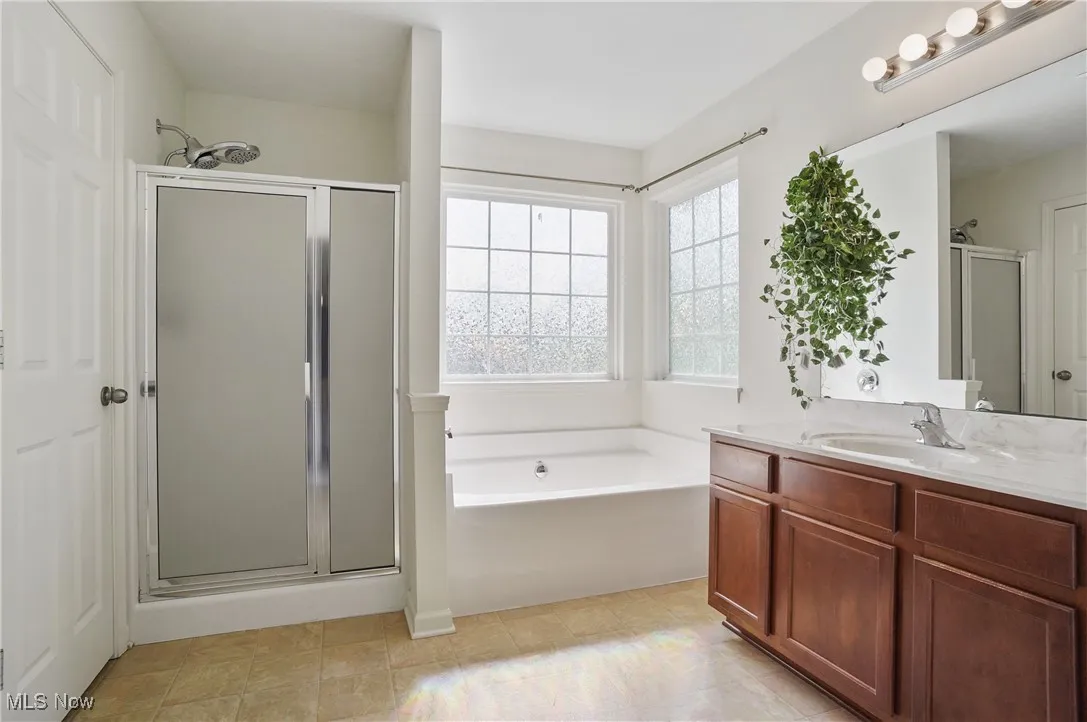 Full bath featuring a bath, vanity, and a shower stall