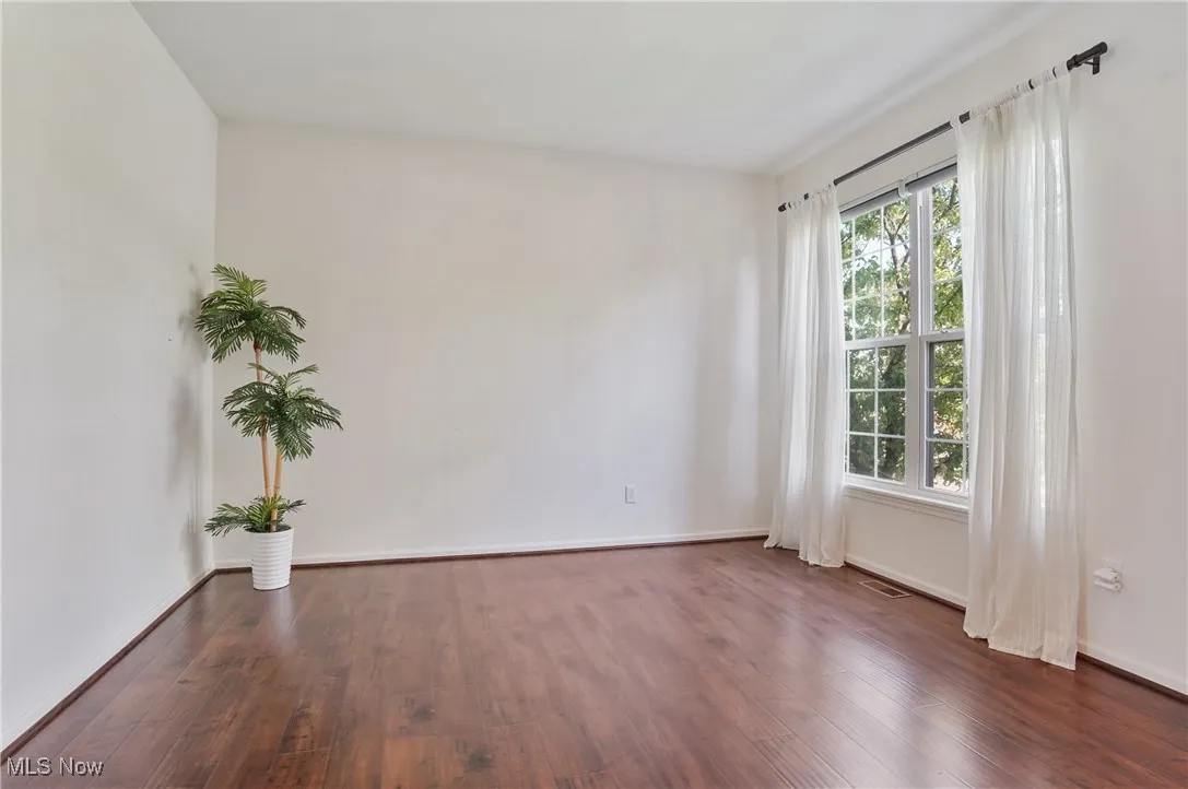 Empty room with baseboards, visible vents, and wood finished floors