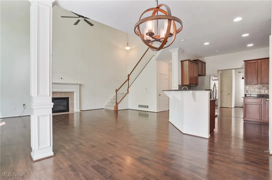 Unfurnished living room featuring recessed lighting, visible vents, ceiling fan with notable chandelier, a tile fireplace, and dark wood-style floors
