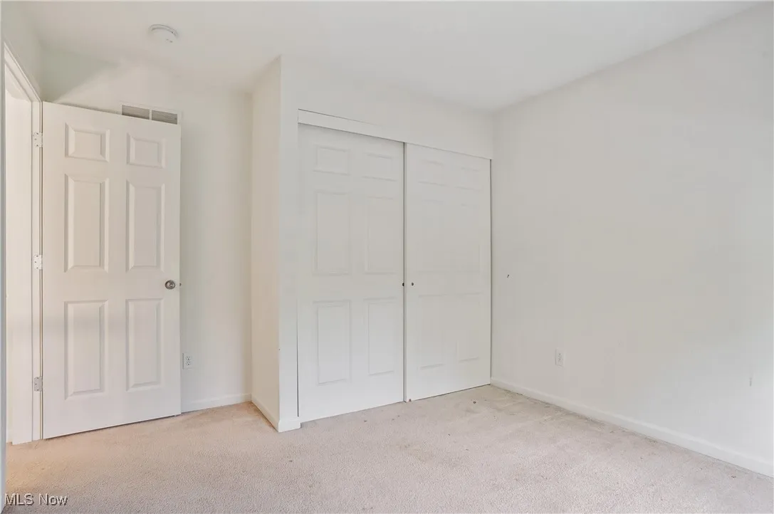 Unfurnished bedroom featuring light colored carpet, a closet, baseboards, and visible vents
