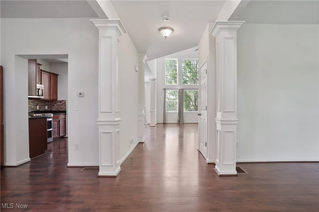 Foyer featuring baseboards, dark wood-style floors, and decorative columns