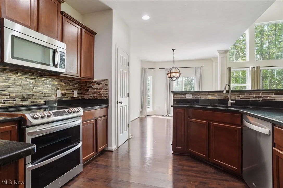 Kitchen with stainless steel appliances, tasteful backsplash, a notable chandelier, and a healthy amount of sunlight