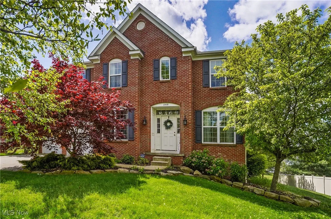View of front of property with driveway, brick siding, a front lawn, and fence