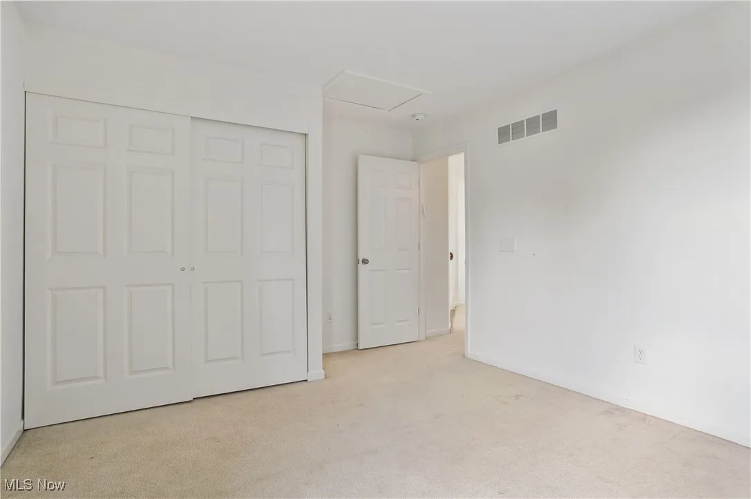 Unfurnished bedroom with a closet, visible vents, baseboards, and light carpet