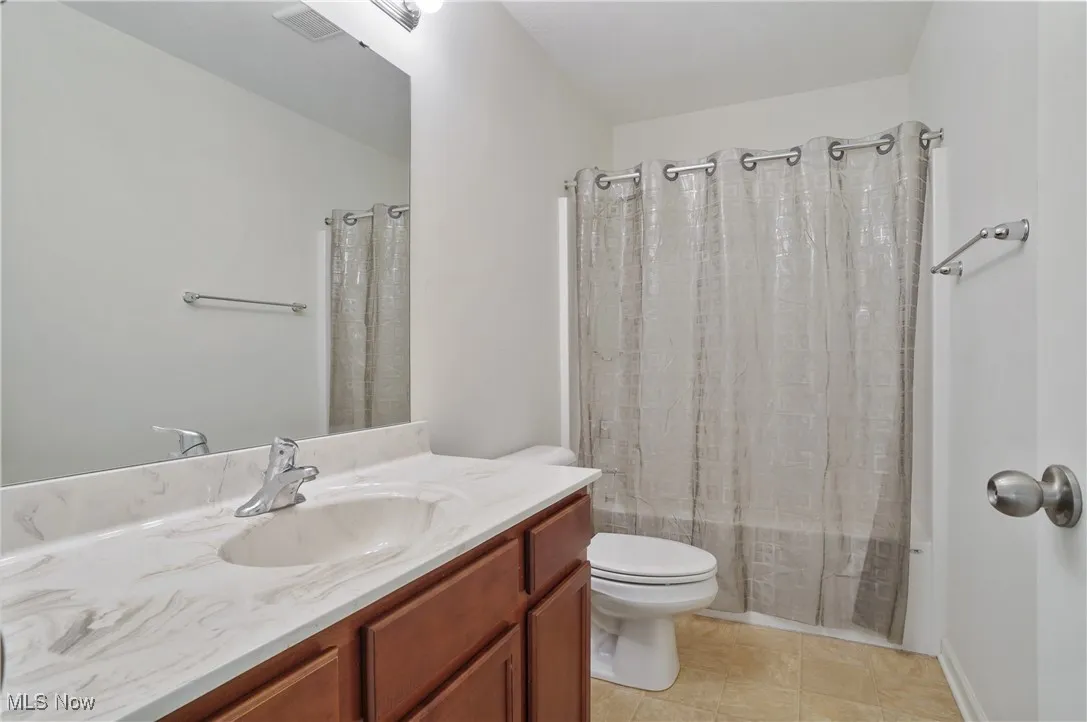 Bathroom with toilet, tile patterned flooring, shower / bath combo, and vanity