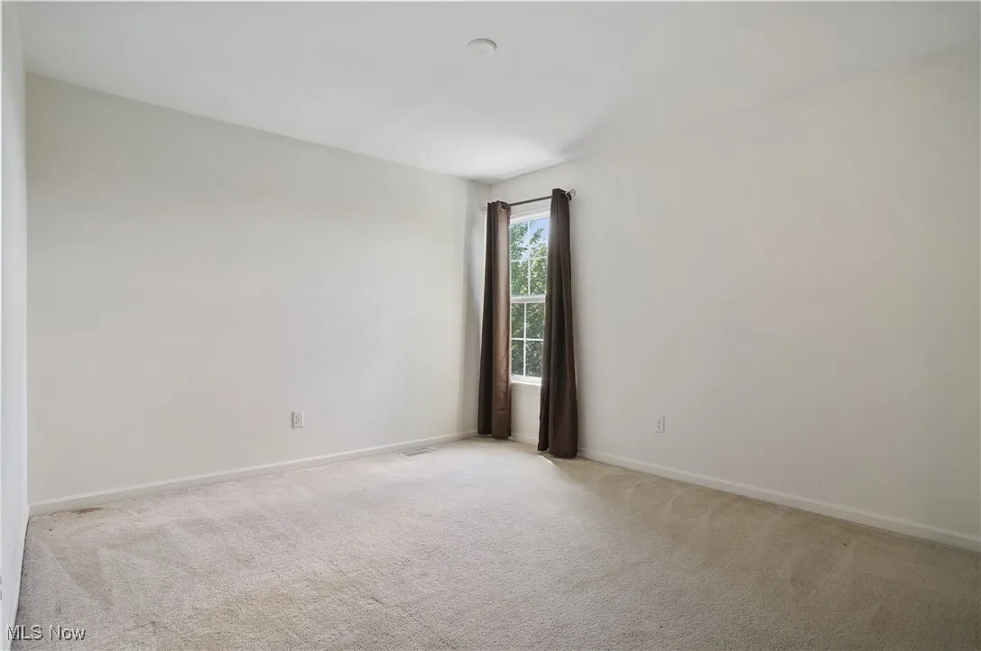 Empty room featuring light carpet, baseboards, and visible vents