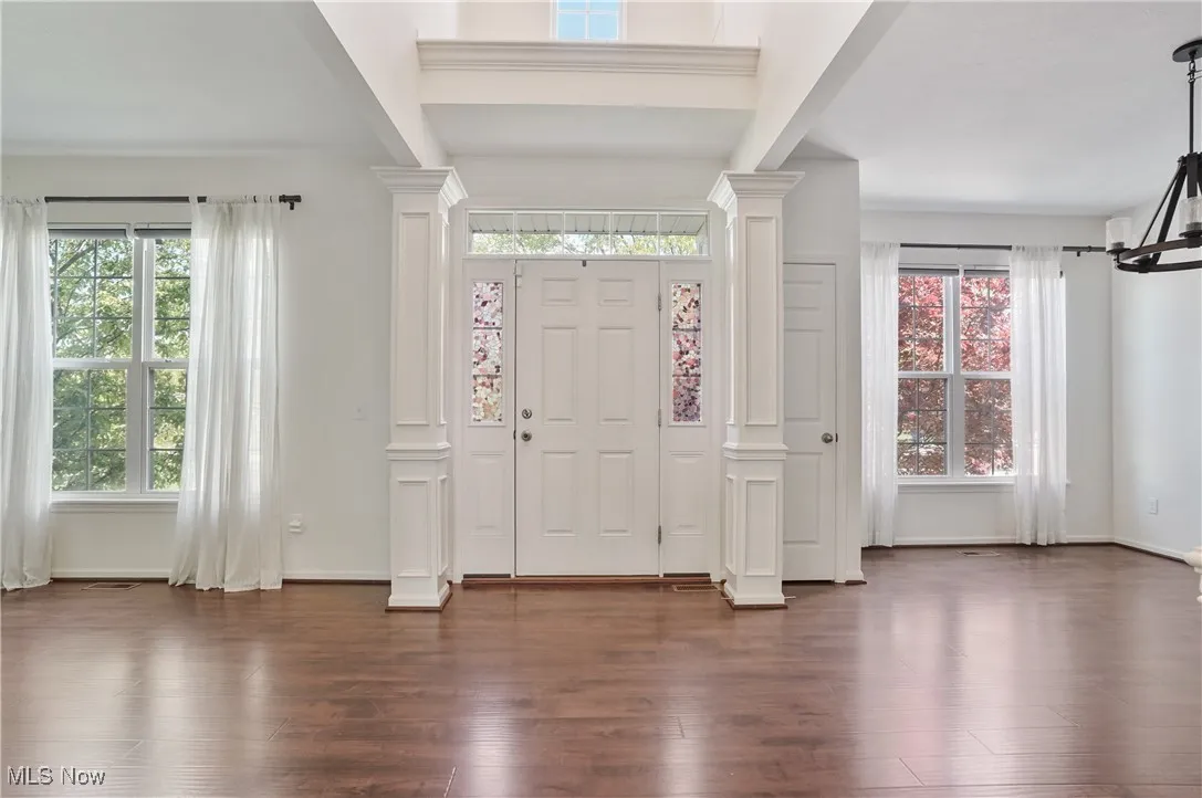 Entrance foyer with baseboards, dark wood-style flooring, and decorative columns