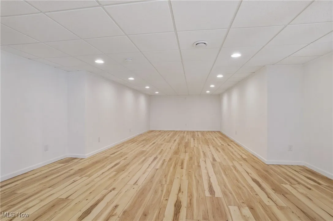 Finished below grade area with a drop ceiling, recessed lighting, baseboards, and light wood-style floors