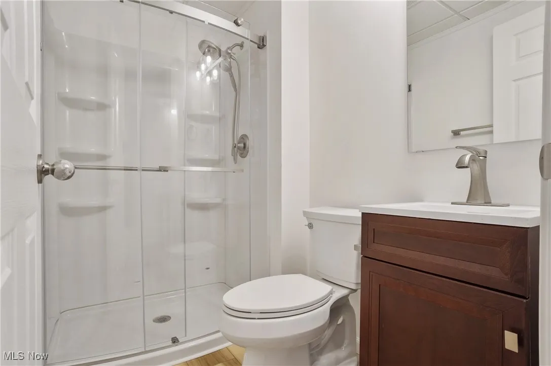 Bathroom with a stall shower, vanity, toilet, and wood finished floors