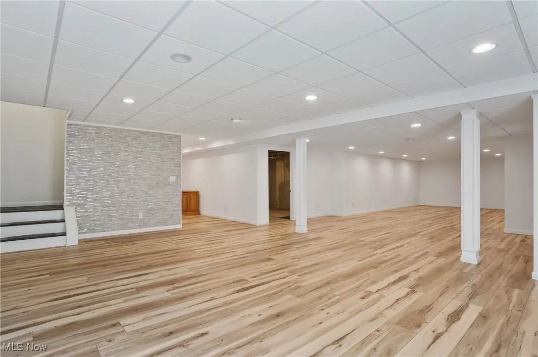 Finished basement with stairs, light wood-style floors, a drop ceiling, and recessed lighting