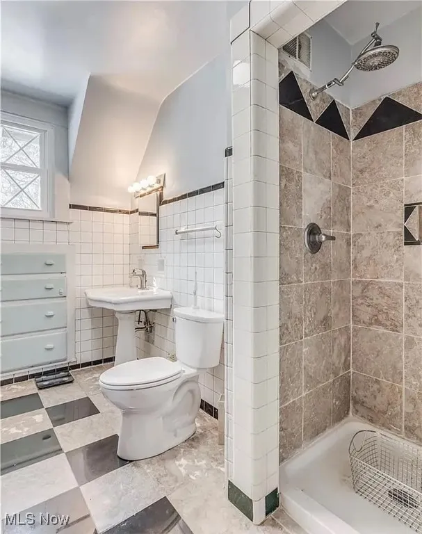 Bathroom with toilet, tile walls, and a shower stall