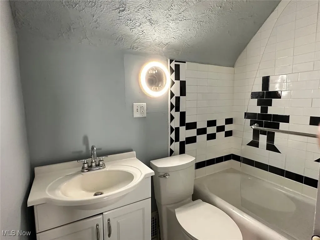Unit 2: 2nd Full Bathroom with vanity, a textured ceiling, toilet, lofted ceiling, and shower / tub combination