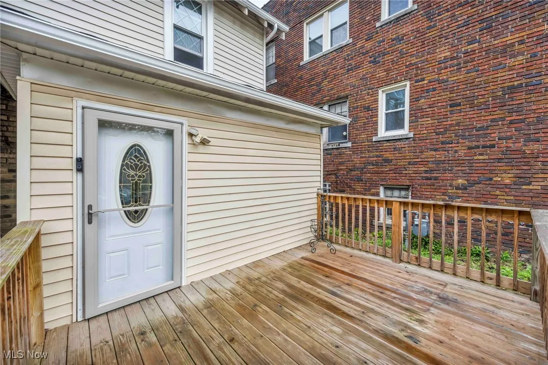 Entrance to property featuring a wooden deck and brick siding