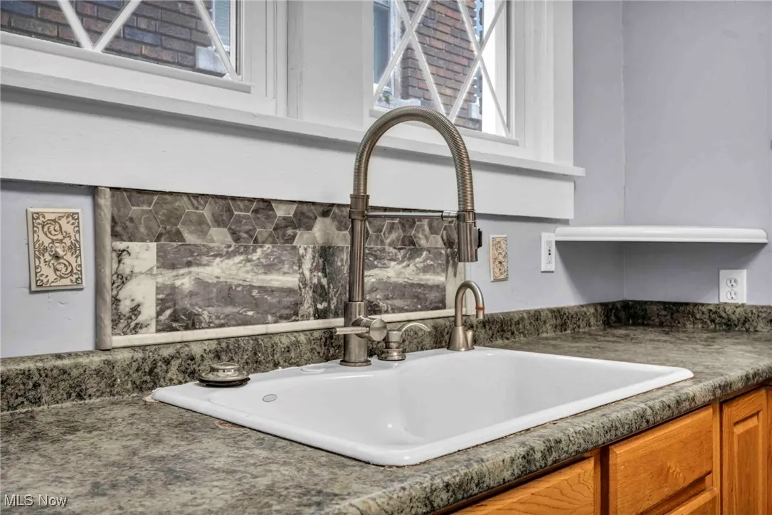 Kitchen view of a sink, dark countertops, and brown cabinets