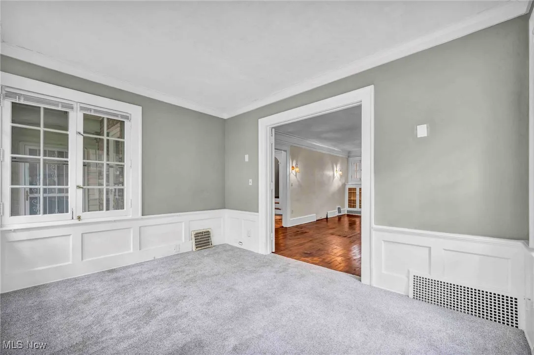 Unfurnished room with carpet floors, ornamental molding, a wainscoted wall, and a decorative wall