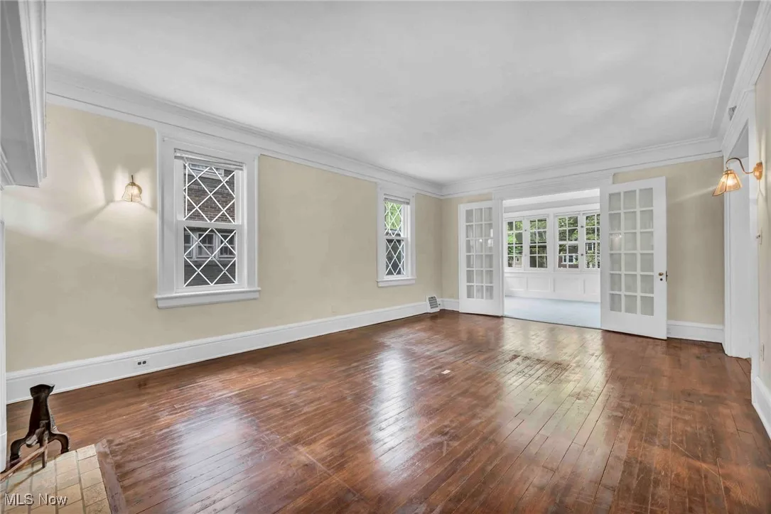 Unfurnished living room with hardwood / wood-style floors, baseboards, and ornamental molding