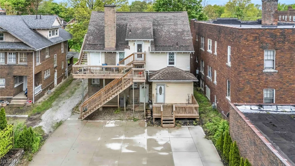Rear view of house featuring a chimney, a wooden deck, stairs, and a patio area