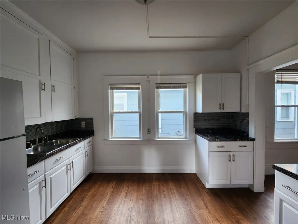 Kitchen with freestanding refrigerator, a sink, plenty of natural light, and tasteful backsplash