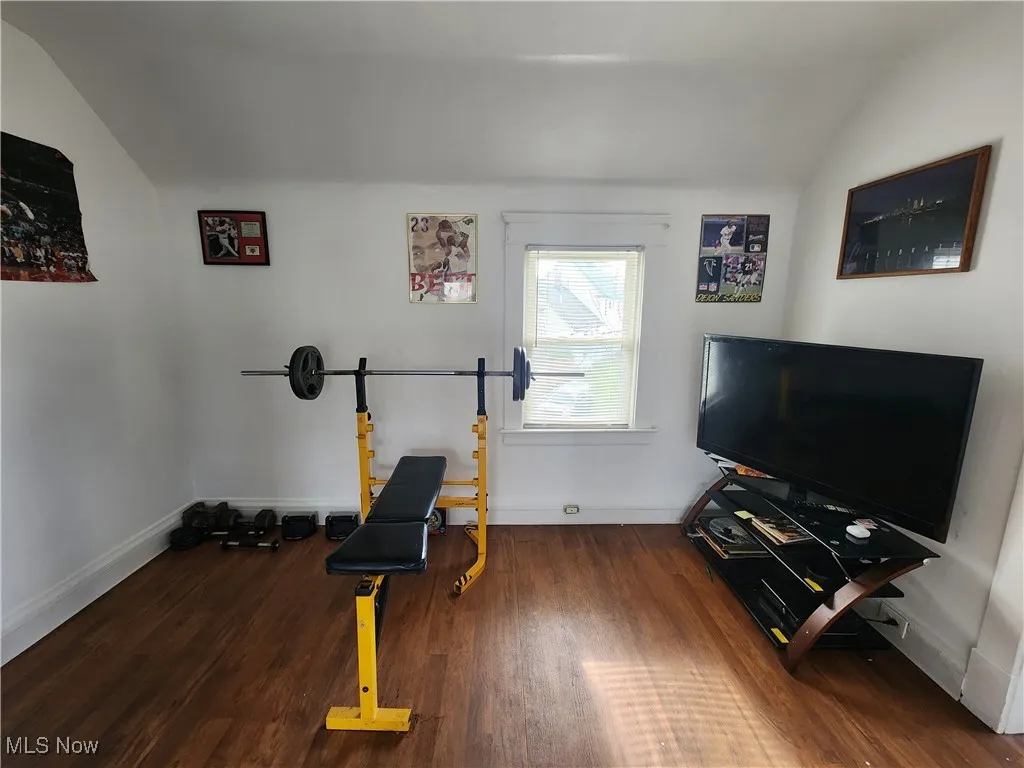 Exercise room with lofted ceiling, wood finished floors, and baseboards