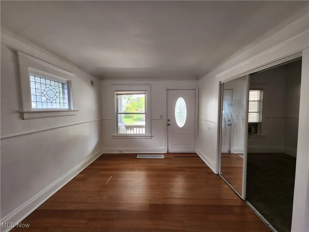 Entrance foyer with healthy amount of natural light, dark wood-style floors, baseboards, and cooling unit