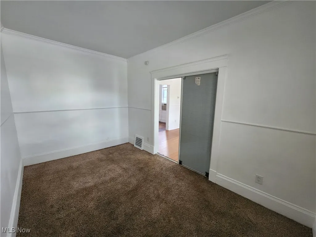 Carpeted spare room with ornamental molding and baseboards