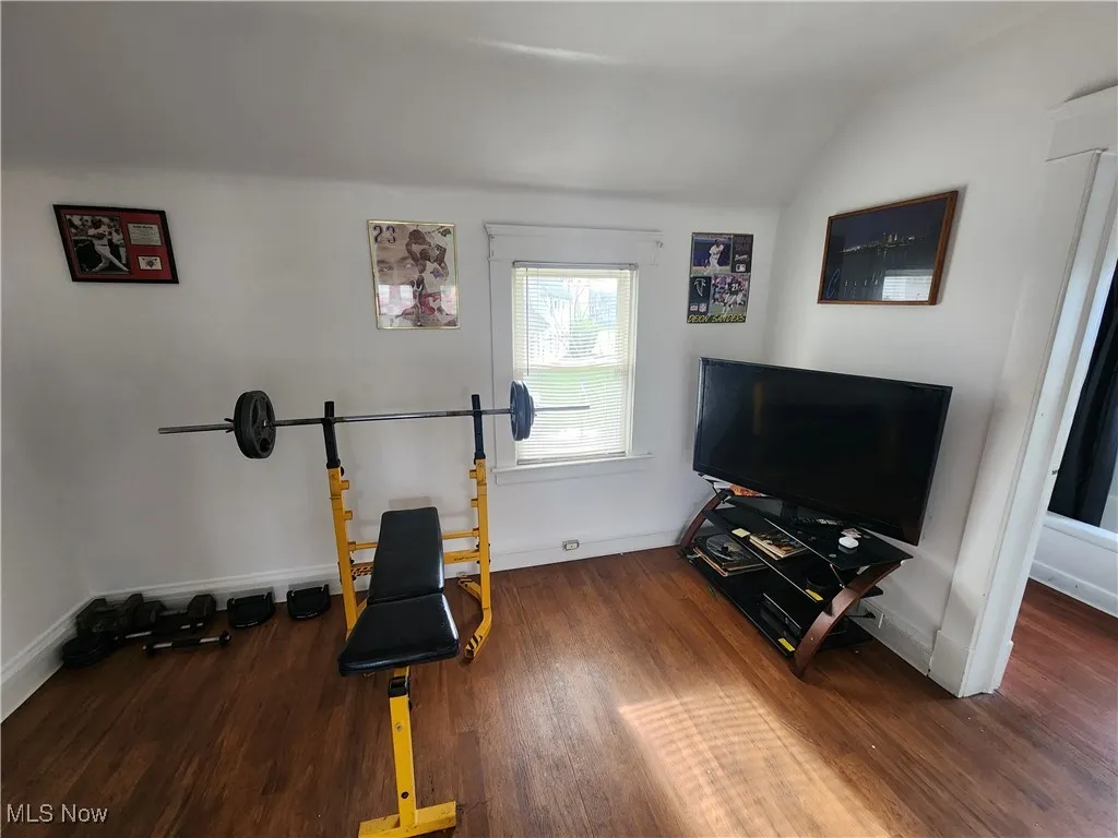 Workout area featuring wood finished floors, baseboards, and lofted ceiling