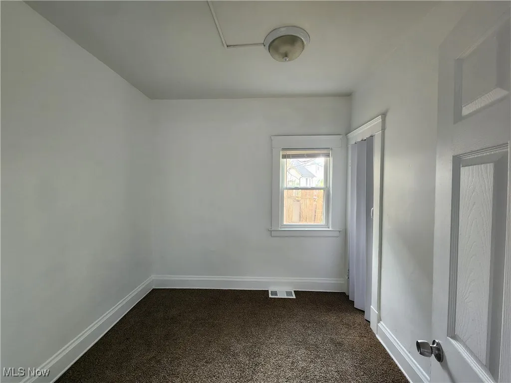 Empty room with dark carpet and baseboards