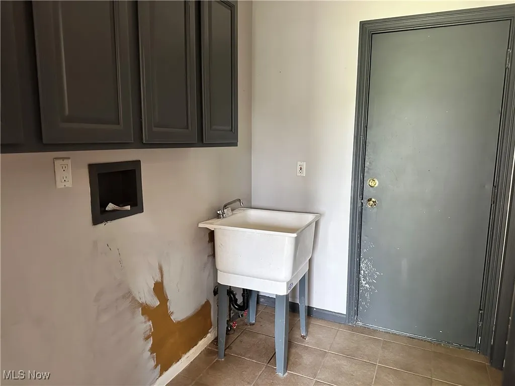 Laundry area with cabinet space, tile patterned flooring, and baseboards