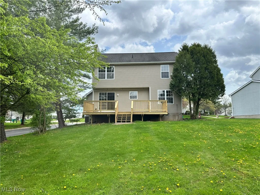 Back of property with a wooden deck and a lawn
