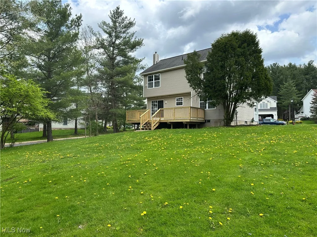 View of grassy yard featuring a wooden deck