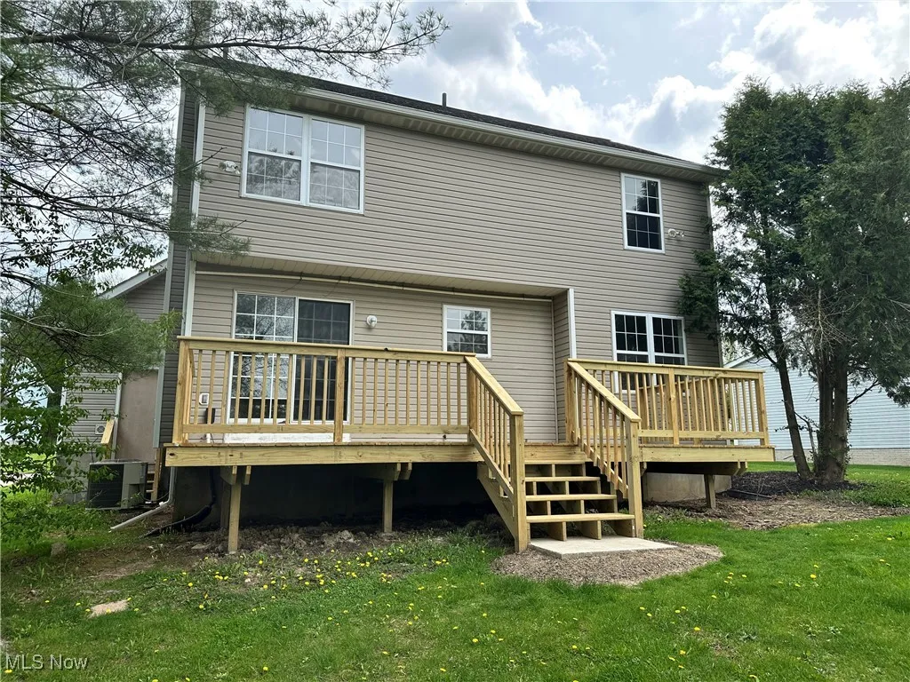 Rear view of house featuring a deck, central AC, and a yard