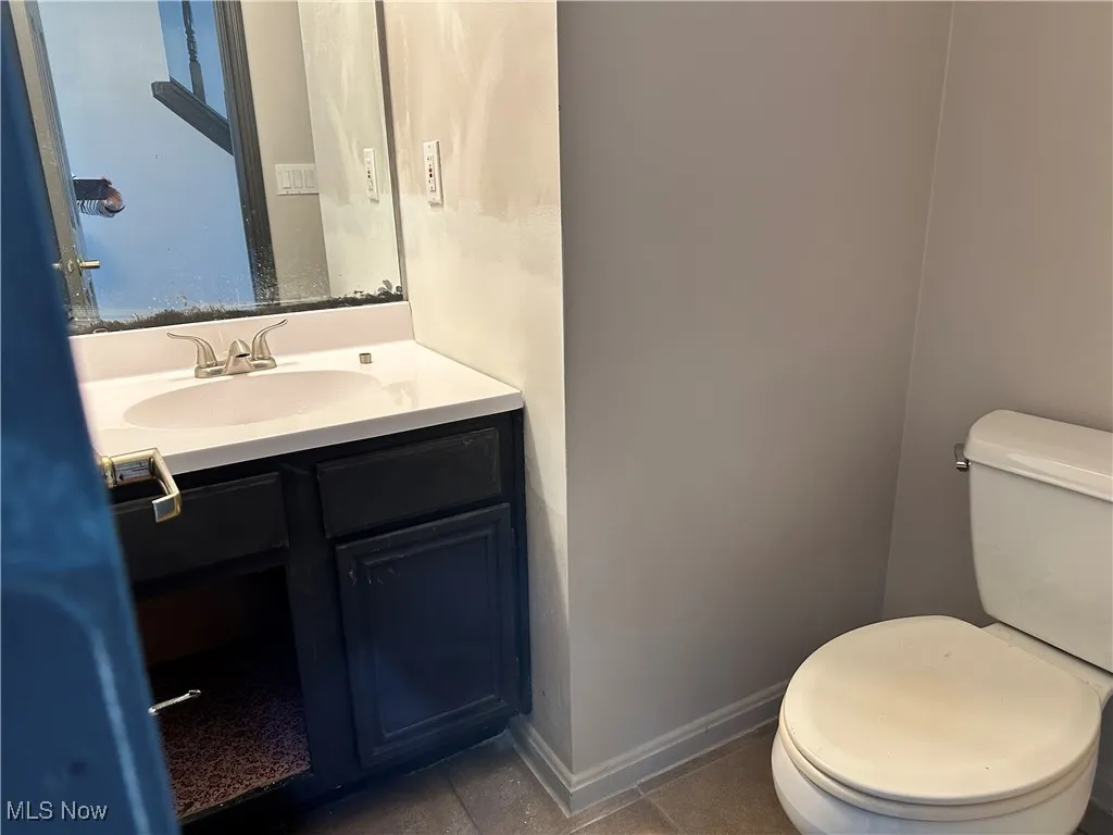 Bathroom with toilet, vanity, and baseboards