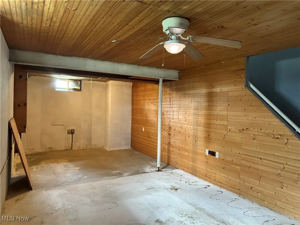 Below grade area featuring ceiling fan, wooden walls, and wood ceiling