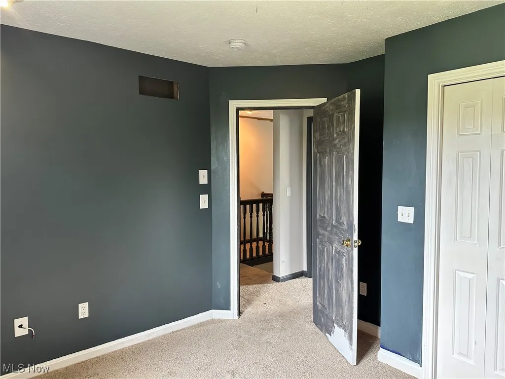 Unfurnished bedroom with carpet, baseboards, and a textured ceiling