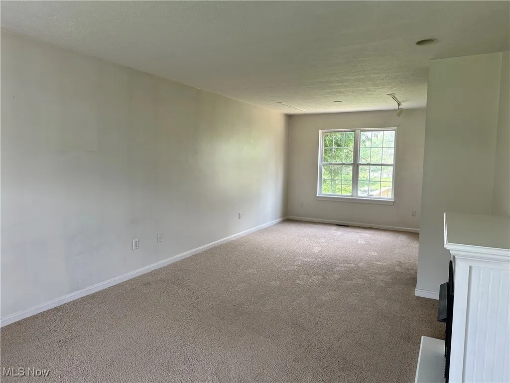 Empty room with carpet floors, baseboards, and a textured ceiling