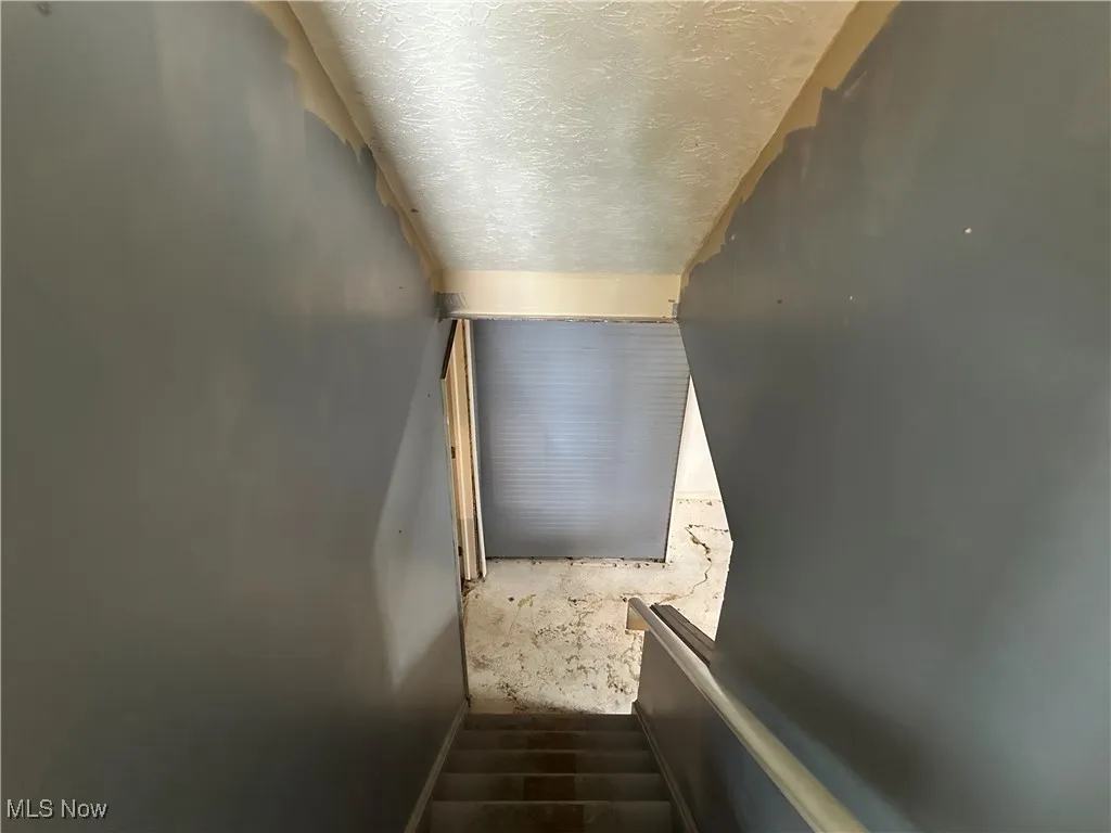 Staircase featuring a textured ceiling