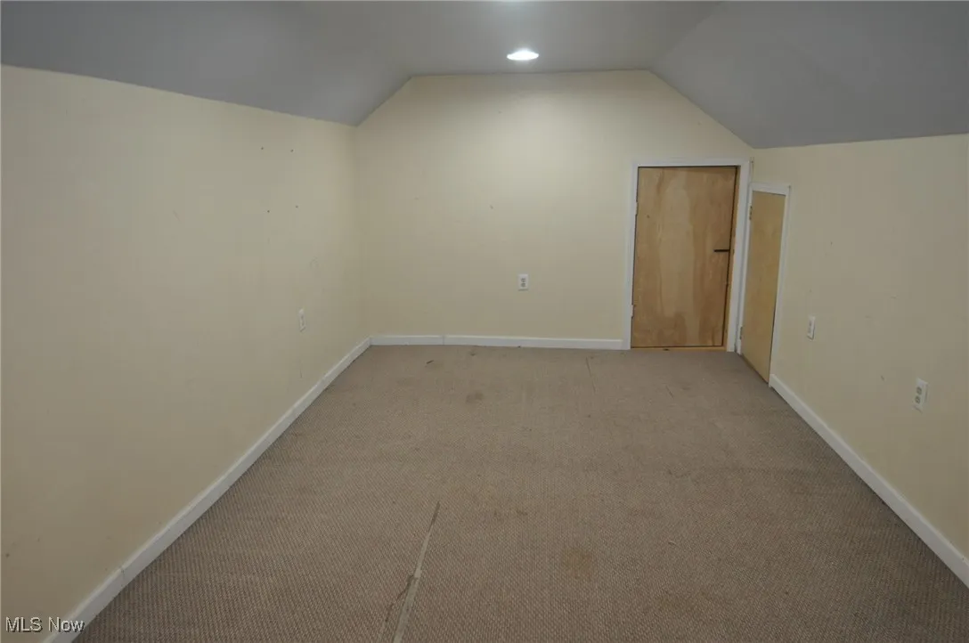 Third floor additional living space with lofted ceiling, carpet, and baseboards