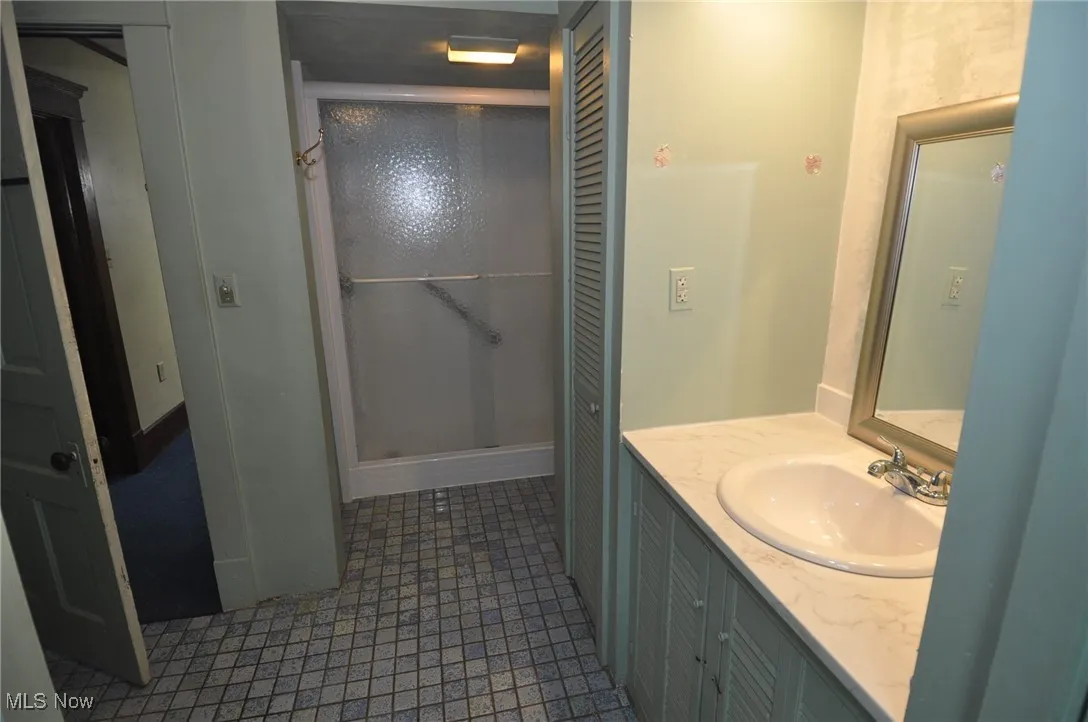 Second floor full hallway bathroom with vanity and a stall shower and closets