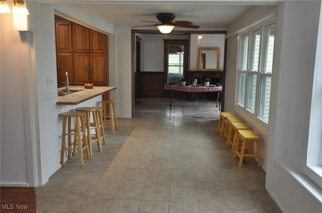 Dining area with plenty of natural light, and light tile patterned floors looking into dining room