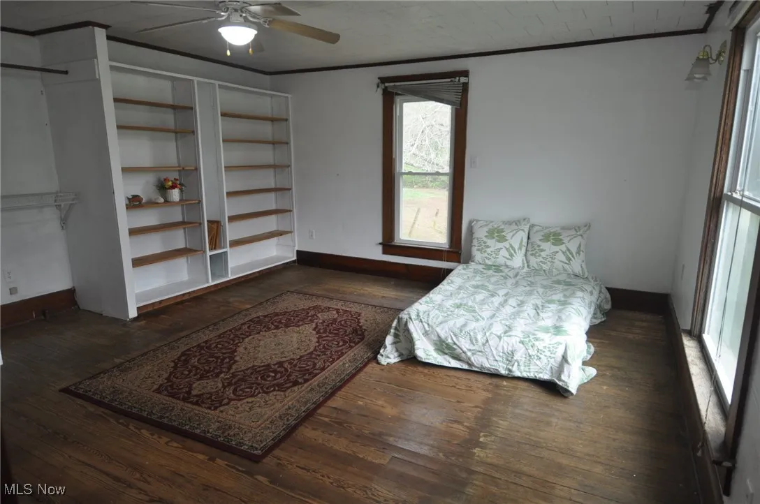 Second floor primary bedroom with crown molding, wood-type flooring, baseboards, a ceiling fan and private bathroom - could be guest room suite
