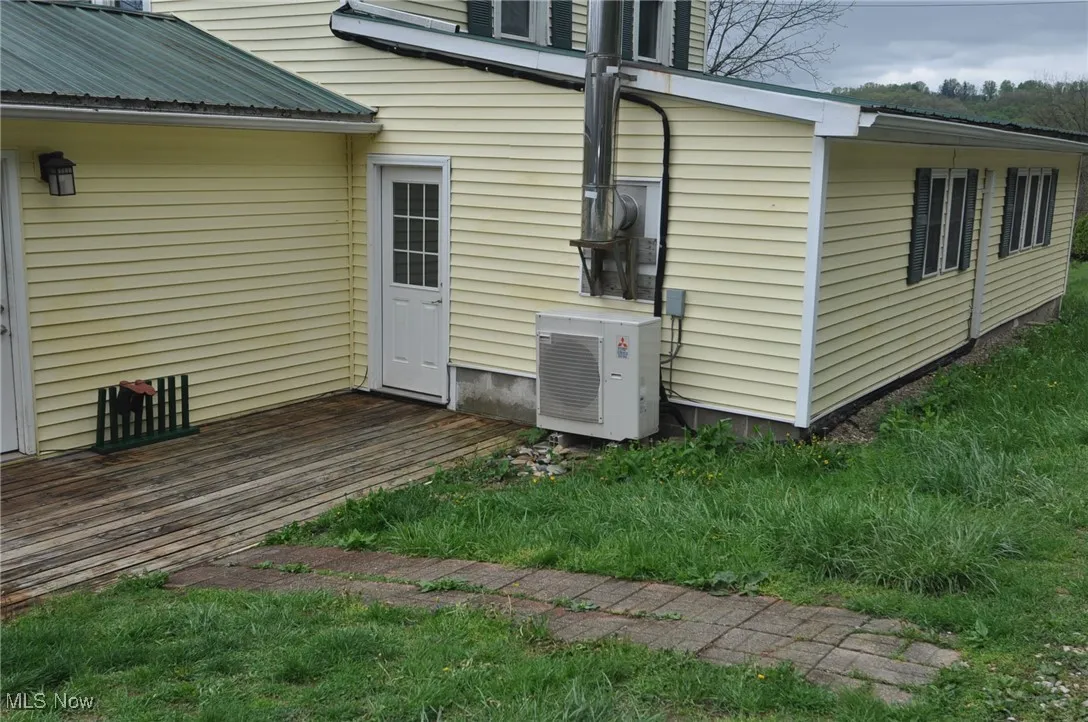 Back of house featuring second generator,, metal roof, and a deck