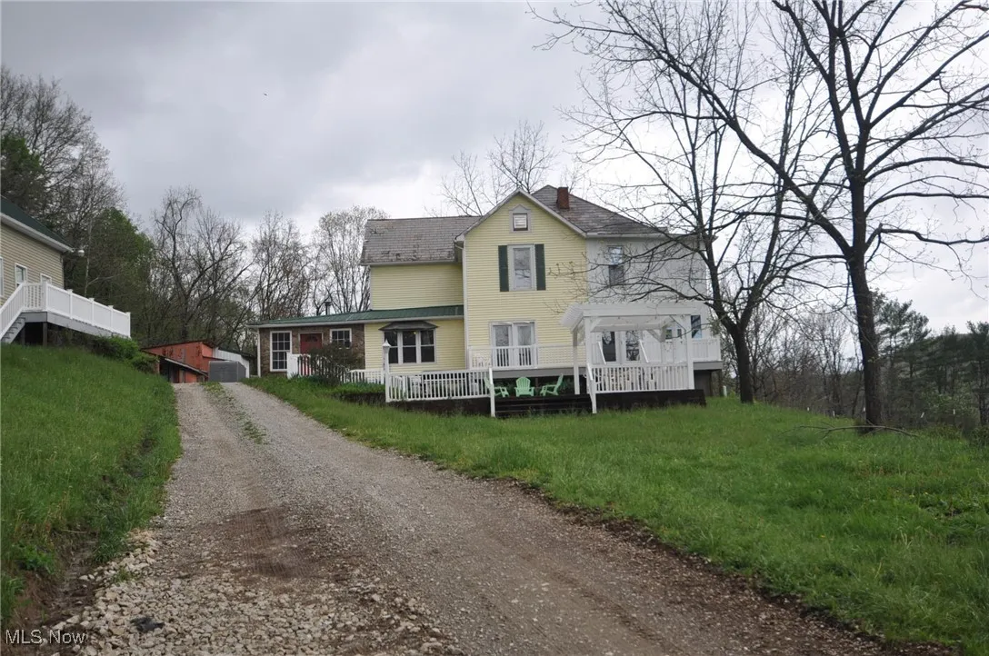 View of front of property with driveway, a chimney, a wooden deck, and roof with shingles