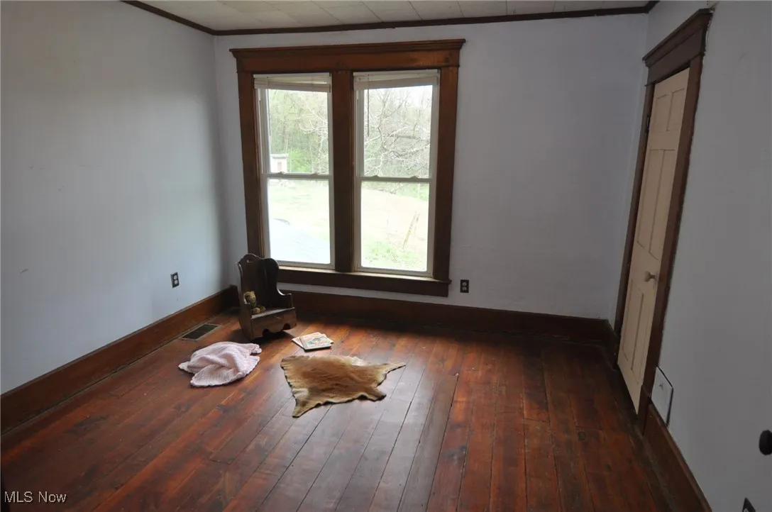 
second floor bedroom with healthy amount of natural light, baseboards, wood-type flooring, and ornamental molding