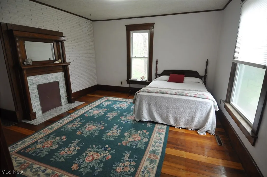 First floor bedroom with decorative fireplace, baseboards, wood floor