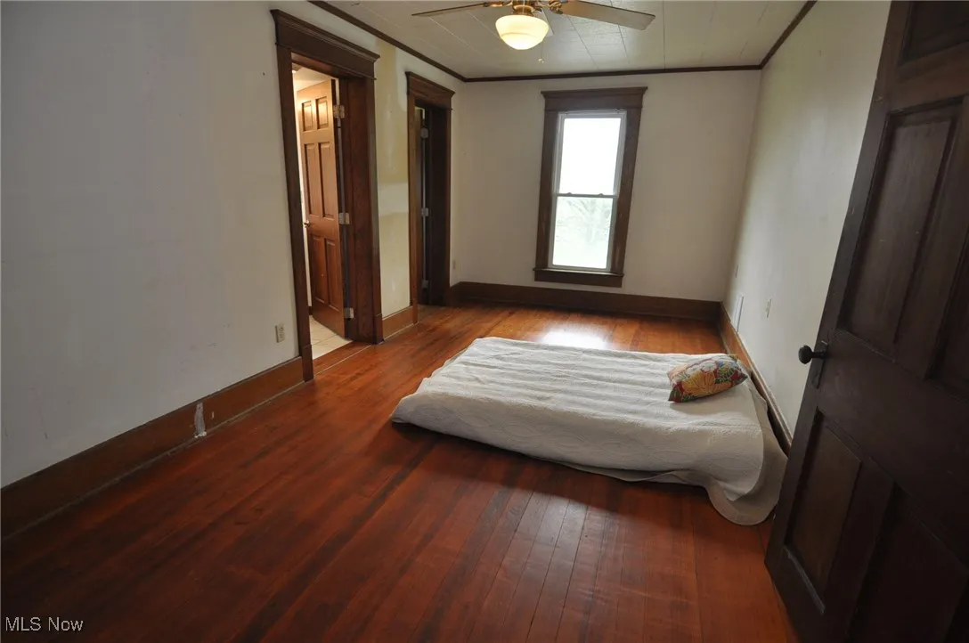Second floor primary bedroom featuring wood finished floors, crown molding, baseboards, ceiling fan and private bathroom
