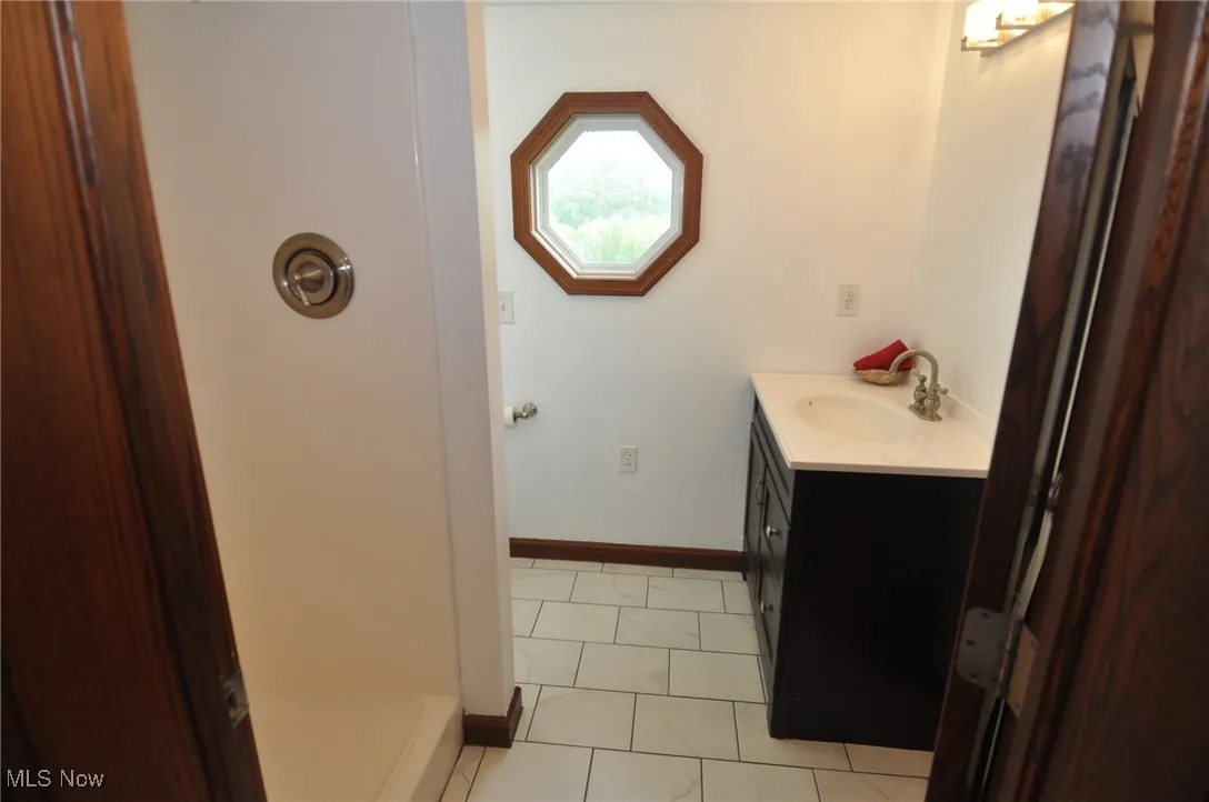 Primary Full bathroom featuring a shower, baseboards, and vanity